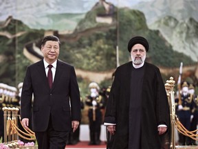 FILE - In this photo released by Xinhua News Agency, visiting Iranian President Ebrahim Raisi, right, walks with Chinese President Xi Jinping after reviewing an honor guard during a welcome ceremony at the Great Hall of the People in Beijing, Tuesday, Feb. 14, 2023. China and Iran have urged mutual neighbor Afghanistan to end restrictions on women's work and education. The call came in a joint statement Thursday, Feb. 16, 2023, issued at the close of Raisi's visit to Beijing in which the sides affirmed close economic and political ties and their rejection of Western standards of human rights and democracy.