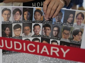 FILE - A supporter holds a placard with the photos of some of the 47 pro-democracy defendants outside a court in Hong Kong, on July 8, 2021. Some of Hong Kong's best-known pro-democracy activists went on trial Monday, Feb. 6, 2023, in the biggest prosecution yet under a law imposed by China's ruling Communist Party to crush dissent. The 18 defendants face up to life in prison if convicted under the national security law critics say is eroding the autonomy promised when Hong Kong returned to China in 1997, and its status as a global business center. They were among 47 pro-democracy figures who were arrested in 2021 under the legislation that was imposed following protests in 2019. They were charged in connection with an informal 2020 primary election.
