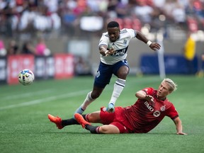 Vancouver Whitecaps' Cristian Dajome, left, is upended by Toronto FC's Lukas MacNaughton during the first half of the Canadian Championship soccer final, in Vancouver, on Tuesday, July 26, 2022. Dajome scored twice in the second half to help the Vancouver Whitecaps blank Toronto FC 3-0 in pre-season play Wednesday at the Coachella Valley Invitational.