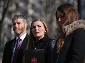 Photojournalist Amber Bracken, centre, lawyer Sean Hern, back left, and Emma Gilchrist, editor-in-chief and executive director of The Narwhal, listen during a news conference after filing a lawsuit at B.C. Supreme Court against the RCMP, in Vancouver, on Monday, Feb. 13, 2023. Bracken was arrested and detained while covering the enforcement of an injunction in Wet'suwet'en territory as a journalist in 2021.