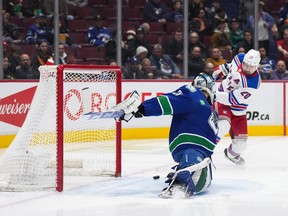 New York Rangers' Chris Kreider, back right, scores against Vancouver Canucks goalie Arturs Silovs during the second period of an NHL hockey game in Vancouver, on Wednesday, February 15, 2023.
