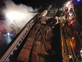 Smoke rises from trains as firefighters and rescuers operate after a collision near Larissa city, Greece, early Wednesday, March 1, 2023.