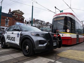 Police cars surround a streetcar on Spadina Avenue in Toronto on Jan. 24, 2023, after a person was stabbed multiple times on the streetcar.