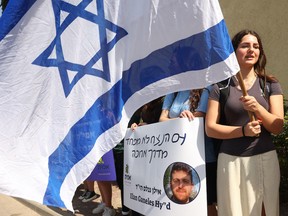 Mourners hold signs outside the cemetery hosting the funeral of Israeli-American Elan Ganeles, who was killed by gunfire near Jericho in the occupied West Bank, on March 1, 2023 in Raanana. (Photo by GIL COHEN-MAGEN / AFP)