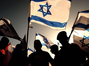 Israeli military veterans wave national flags during a rally against the government's judicial reform bill, along a highway near Netanya on March 28, 2023. (Photo by JACK GUEZ / AFP)