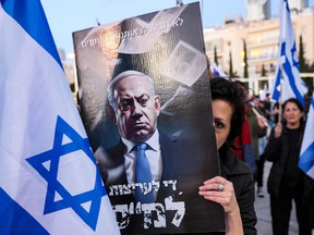 A demonstrator covers her face with a sign against Israeli Prime Minister Benjamin Netanyahu during a march against the government's judicial reform bill, in Tel Aviv on April 1.