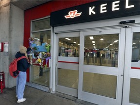 A woman places flowers at a makeshift memorial at the TTC's Keele subway station for Gabriel Magalhaes, who was stabbed to death two days earlier in an unprovoked attack, March 27, 2023.