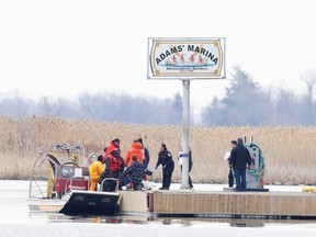 Police and firemen carry a bag off their search boat from the marshland in Akwesasne, Que., March 31.