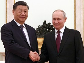 Russian President Vladimir Putin shakes hands with Chinese President Xi Jinping.