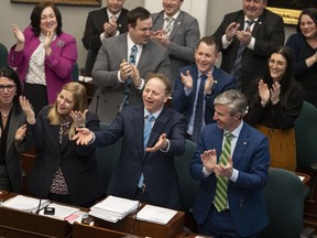Finance and Treasury Board Minister Allan MacMaster, second from bottom right, standing beside Premier Tim Houston, bottom right, gestures to the opposition parties while tabling the provincial budget at the Nova Scotia legislature in Halifax on Thursday, March 23, 2023.