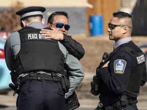 Peace officers hug during the procession for Constable Travis Jordan and Constable Brett Ryan in Edmonton on Tuesday March 21, 2023. A regimental funeral is set to be held today for two Edmonton police officers who were shot and killed by a 16-year-old boy.