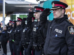 City police salute during the procession for Edmonton Police Service constables Travis Jordan and Brett Ryan in Edmonton, Monday, March 27, 2023. Police say more people are interested in joining the Edmonton police after two officers were killed responding to a call earlier this month.