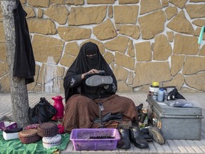 An Afghan woman cleans customers's shoes in a street in Kabul, Afghanistan, Sunday, March 5, 2023. After the Taliban came to power in Afghanistan, women have been deprived of many of their basic rights.