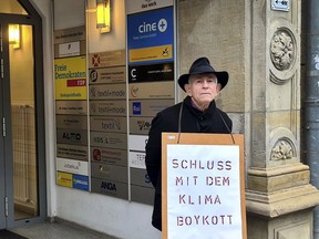 Father Reinhart Kraft of the 'Ecumenical Ecology Group Lichtenrade' poses with a protest poster in front of the headquarters of the German Liberal Party (FDP) in Berlin, Germany, Friday, March 3, 2023. The Free Democrats, a small pro-business party that controls Germany's Ministry of Transport, has pushed back against efforts to impose a general speed limit, phase out combustion engines and reduce road building. Slogan reads: 'End the climate boycott'.
