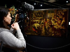 A journalist films the painting 'Le paiement de la dime' (The Payment of the Yearly Dues) by the artist Pieter Brueghel the Younger (1564-1636) before its auction at Drouot auction house in Paris, France.