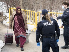 RCMP officers approach a woman entering Canada via Roxham road on the Canada/US border in Hemmingford, Que., Saturday, March 25, 2023.