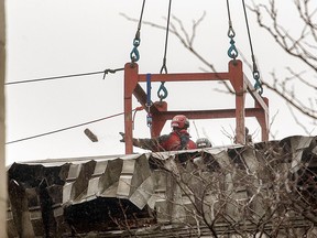 Workers remove rubble from a building that was gutted by a fire in Montreal, Thursday, March 23, 2023. More than a week after a fatal fire tore through a building in Old Montreal, accounts from former tenants and victims of the blaze are raising questions about the safety of the heritage property.