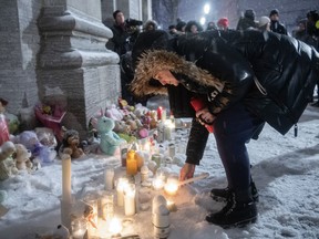 A woman lights a candle during a vigil at a church near the site of a daycare centre where two children lost their lives after a city bus crashed into the building in Laval, Que, Thursday, February 9, 2023.&nbsp;A Quebec man accused of killing two young children by driving a city bus into a Montreal-area daycare will remain detained in a psychiatric institution for another 30 days. THE&nbsp;CANADIAN PRESS/Graham Hughes