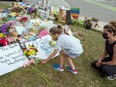 A child leaves flowers at a makeshift memorial at the scene where a Muslim family was killed in what police describe as a hate-motivated attack, at the London Muslim Mosque in London, Ont., June 12, 2021.
