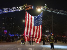 Chicago firefighters set up a large American flag outside the Cook County Medical Examiner's Office for a procession carrying the remains of a police officer who was shot on Wednesday, March 1, 2023. The officer was shot on the city's Southwest Side while responding to a call of a man chasing a woman with a gun, Police Superintendent David Brown said.