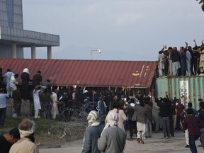 Supporters of former Prime Minister Imran Khan remove a shipping container after clashes with police at outside the a court, in Islamabad, Pakistan, March 18, 2023. Pakistani police stormed former Prime Minister Khan's residence in the eastern city of Lahore on Saturday and arrested 61 people amid tear gas and clashes between Khan's supporters and police, officials said.