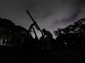 FILE - A girl looks at the moon through a telescope in Caracas, Venezuela, on Sunday, May 15, 2022. The best day to spot five planets, Mercury, Jupiter, Venus, Uranus and Mars, lined up in the night sky is Tuesday, March 28, 2023, right after sunset. The five-planet array will be visible from anywhere on Earth, as long as you have clear skies.
