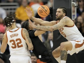 Miami guard Isaiah Wong drives to the basket between Texas forward Christian Bishop (32) and forward Timmy Allen in the first half of an Elite 8 college basketball game in the Midwest Regional of the NCAA Tournament Sunday, March 26, 2023, in Kansas City, Mo.