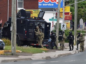 Emergency response officers enter a residence in Moncton, N.B., on Thursday, June 5, 2014.