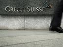 A pedestrian walks past a logo of Credit Suisse outside its office building in Hong Kong, China.