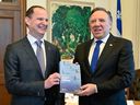Quebec Finance Minister Eric Girard, left, and Quebec Premier Francois Legault hold a copy of the budget speech, at the premier's office in Quebec City. 