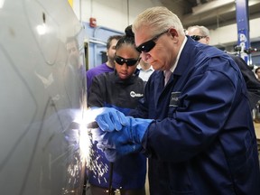 Ontario Premier Doug Ford, right, gets help from grade 11 student Shannon Williams, 16, as they practise plasma welding on a car hood while visiting St. Mary Catholic Secondary School in Pickering, Ont., on Wednesday, March 8, 2023.