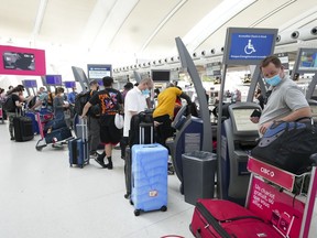 People wait in line to check in at Pearson International Airport in Toronto on Thursday, May 12, 2022. Canadian travellers are facing increased airport fees after the pandemic grounded revenues and led to accumulating debt for airports across the country.