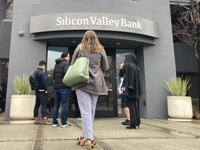 File - People stand outside of an entrance to Silicon Valley Bank in Santa Clara, Calif., Friday, March 10, 2023. The collapse of Silicon Valley Bank and Signature Bank, and the bailout of First Republic, was a jolt for small businesses of all stripes, spurring many to scrutinize their banking services and mull whether or not they should make changes to ensure their money is safe.