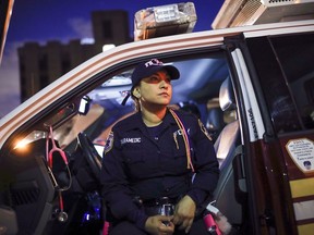 FILE -- FDNY paramedic Elizabeth Bonilla wears her multicolored braids as she sits in her ambulance between calls after delivering a patient to Jacobi Medical Center, April 15, 2020, in the Bronx borough of New York. Four New York City ambulance workers, including Bonilla, who said they were disciplined for speaking to the media during the first harrowing months of the COVID-19 pandemic, have reached a settlement in their free speech lawsuit against the fire department and the city, their union announced Wednesday, March 1, 2023.
