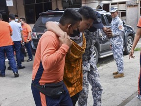 Rescuers assist a survivor of the MV Lady Mary Joy fire as some of the survivors arrive in Zamboanga, southern Philippines Thursday March 30.