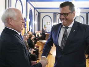 Saskatchewan Agriculture Minister David Marit, left, shakes the hand of Health Minister Paul Merriman, right, at a press conference at Government House in Regina on Tuesday May 31, 2022 as the government announced a cabinet shuffle.