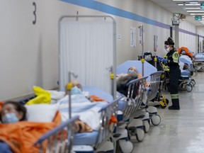 A paramedic tends to a patient in a hallway at the Humber River Hospital in Toronto on Tuesday, January 25, 2022.