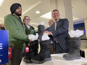 Manitoba Finance Minister Cliff Cullen gives two pairs of winter boots to members of the Downtown Community Safety Partnership in Winnipeg, Monday, March 6, 2023. Cullen made the donation a day before he was scheduled to deliver the provincial budget.