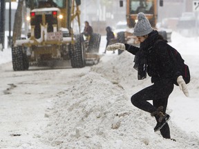 A pedestrian makes her way over a snowbank left behind as graders cleared snow in Edmonton. Residents in some Toronto-area cities have become angry over large snowbanks and blocked driveways caused by plows.