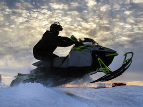 A snowmobiler warms up at an event on Sturgeon Lake in the city of Kawartha Lakes, Ont., Sunday, February 20, 2022. A snowmobile race in Labrador that bills itself as the longest and toughest in the world has been cancelled mid-course because of rain and broken sea ice. THE CANADIAN PRESS/Fred Thornhill