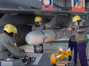 In this photo released by the Taiwan Presidential Office, ground crew attach a missile to the wing of an F-16 jet fighter at Air Force base during a visit by Taiwanese President Tsai Ing-wen, at a military base in Chiayi, southwestern Taiwan on Jan. 6.