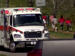 Children run past an ambulance near the Covenant School after a shooting in Nashville, Tennessee, U.S. March 27, 2023 in a still image from video.