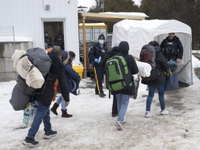Oficiales de la RCMP reciben a una familia de solicitantes de asilo de Colombia en Wroxham Road en Champlain, Nueva York, el jueves 9 de febrero de 2023, después de viajar a Canadá desde Nueva York.  Los defensores de la inmigración dicen que están decepcionados de que Canadá y Estados Unidos hayan aceptado las restricciones.  Los solicitantes de asilo fluyen a través de su frontera compartida.