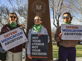 Three members of the Women's March group protest in support of access to abortion medication outside the Federal Courthouse on Wednesday, March 15, 2023 in Amarillo, Texas.