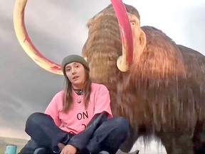 A climate activist makes a statement after defacing the Royal B.C. Museum's mammoth.