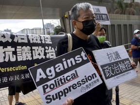 FILE - Pro-democracy activist Lee Cheuk-yan, center, holds placards as he arrives at a court in Hong Kong Thursday, April 1, 2021. Hong Kong national security police arrested Thursday, March 9, 2023, Lee Cheuk-yan's wife Elizabeth Tang, herself a labor activist with the now-defunct Hong Kong Confederation of Trade Unions. Lee is a prominent activist who was among the leaders of a group that organized annual vigils commemorating China's 1989 crackdown on pro-democracy protesters.