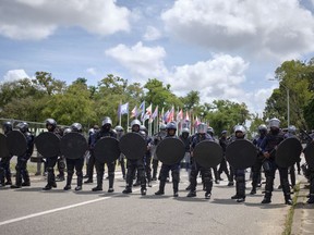Security forces stand guard in the area of parliament on the sidelines of an anti-government protest in Paramaribo, Suriname, Friday, March 24, 2023. Protesters are demanding that the president resign.