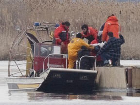 A bag is lifted off a fire service boat onto a dock during the search for drowning victims in a marsh in Akwesasne, west of Montreal, on Friday, March 31, 2023.