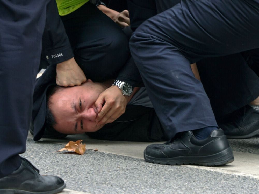 In this photo taken on Sunday, Nov.  27, 2022, policemen pin down and arrest a protester during a protest on a street in Shanghai, China.