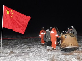 Researchers work around Chang'e-5 lunar return capsule carrying moon samples next to a Chinese national flag, after it landed in northern China's Inner Mongolia Autonomous Region, December 17, 2020.